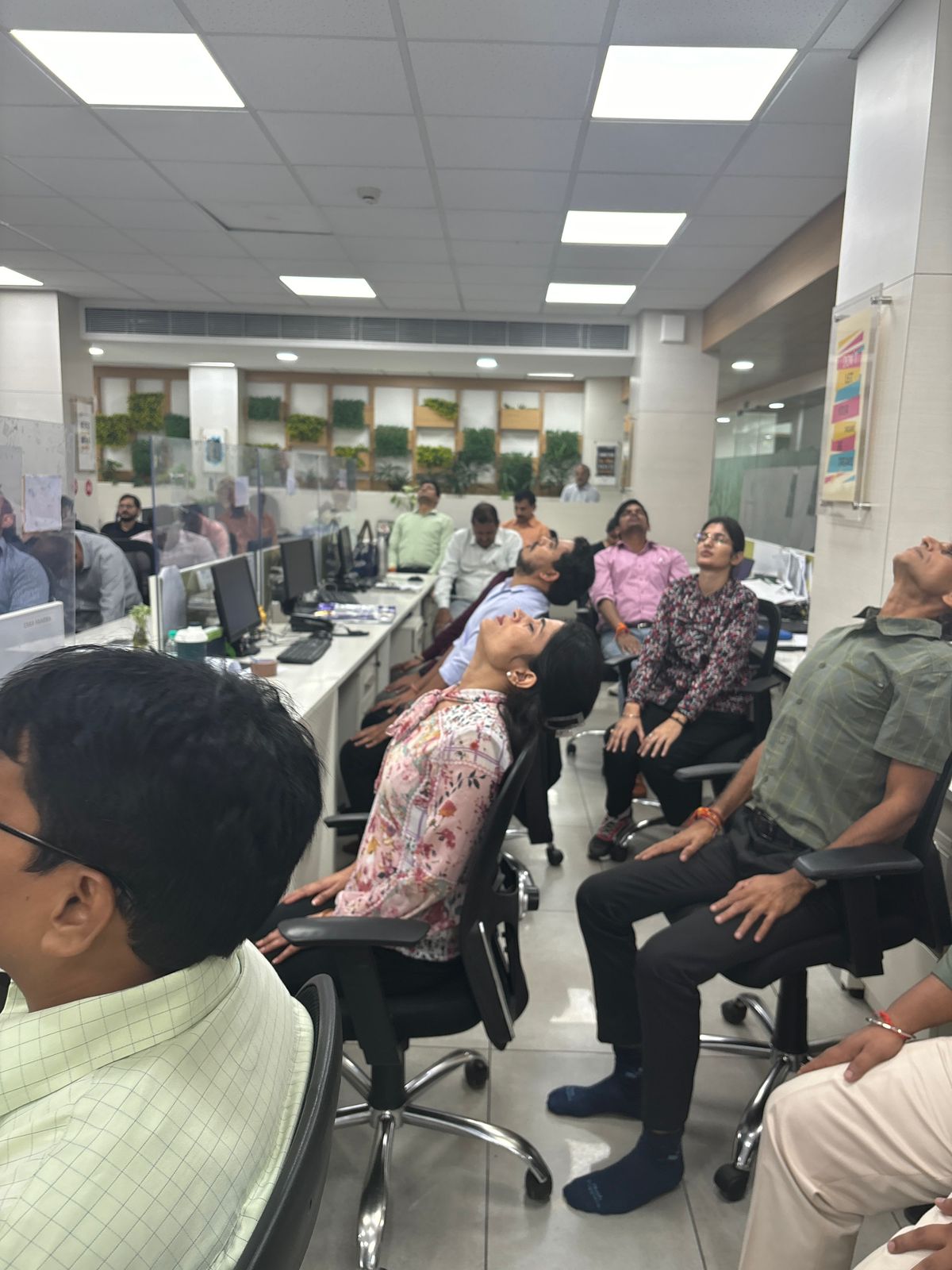 Corporate employees performing synchronized stretches during an office yoga session