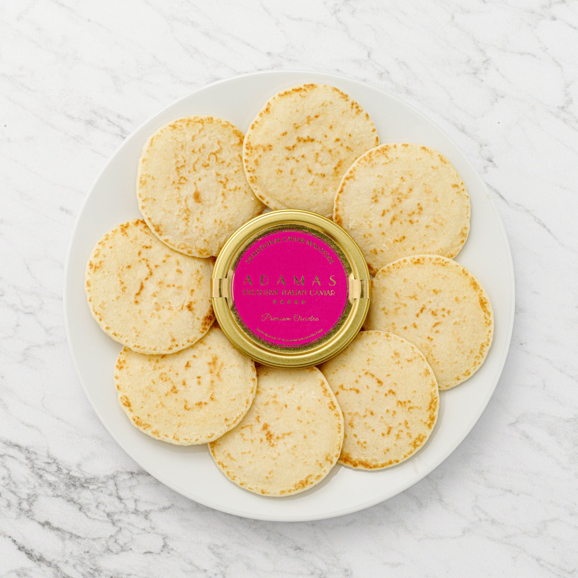 Caviar tin with blinis flat lay on marble background - product photography UK