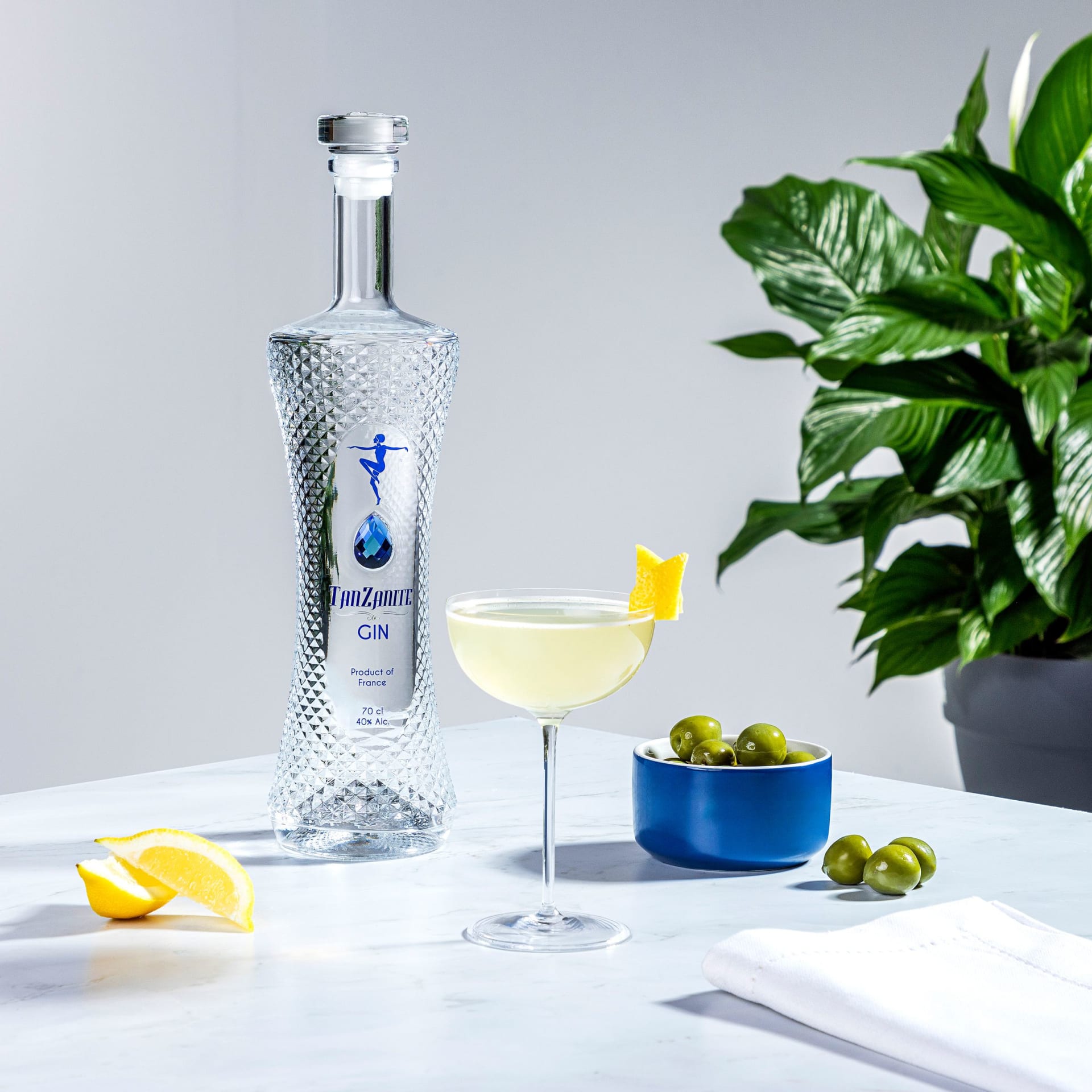 Gin bottle cocktail with olives and lemon on marble lifestyle photography - drinks styling UK