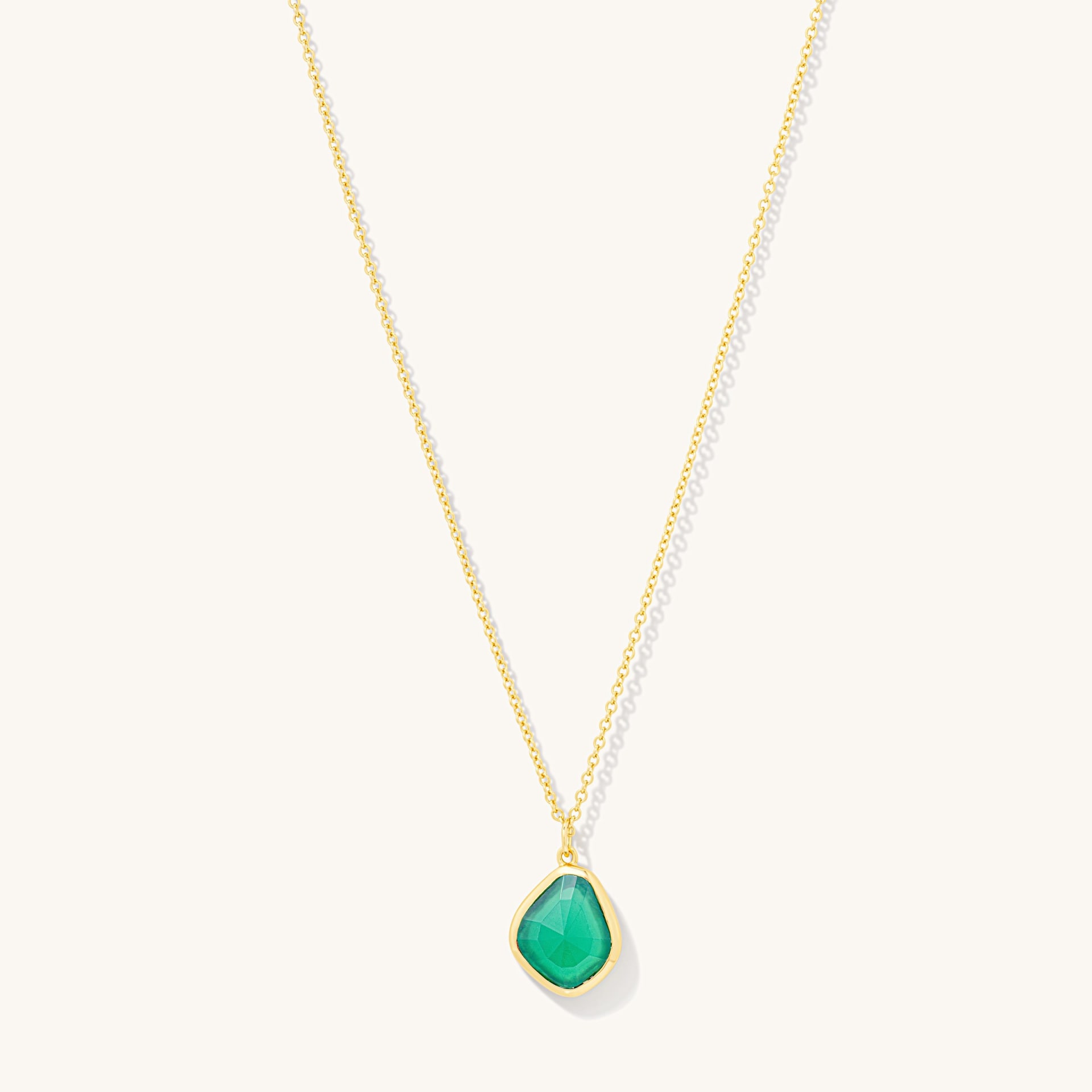 Gold pendant necklace with green gemstone on white - fine necklace photography UK
