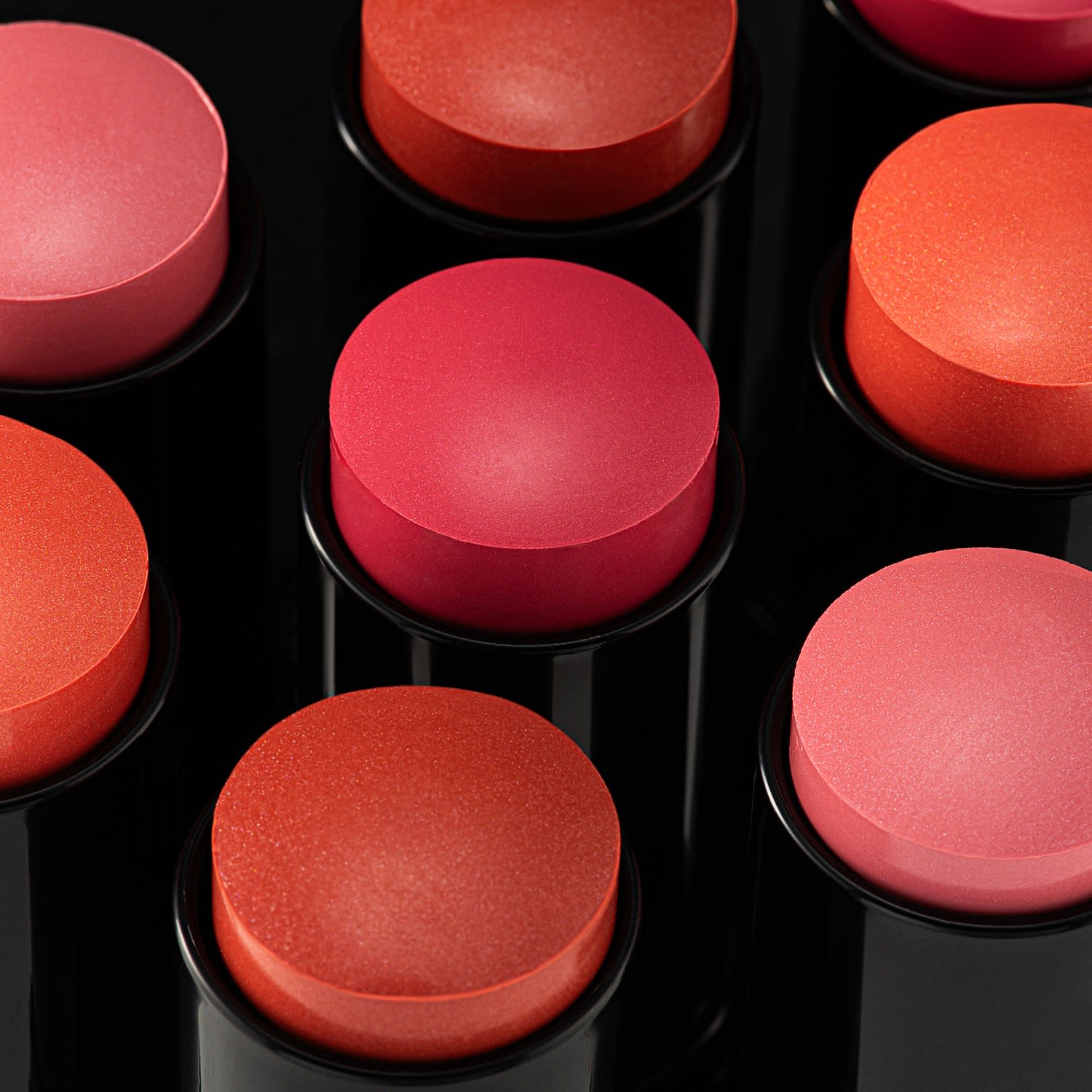 Pink, coral and red blush sticks photographed close up to show their shades and surface texture