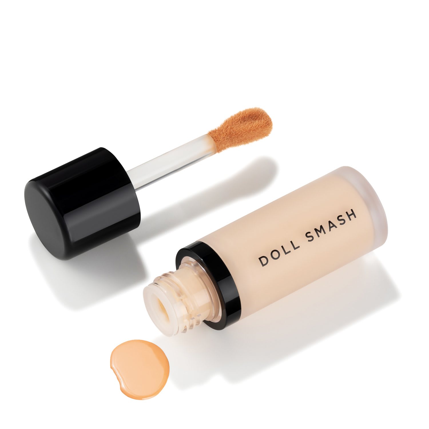 Open Doll Smash concealer bottle with its wand and a drop of formula arranged diagonally on white