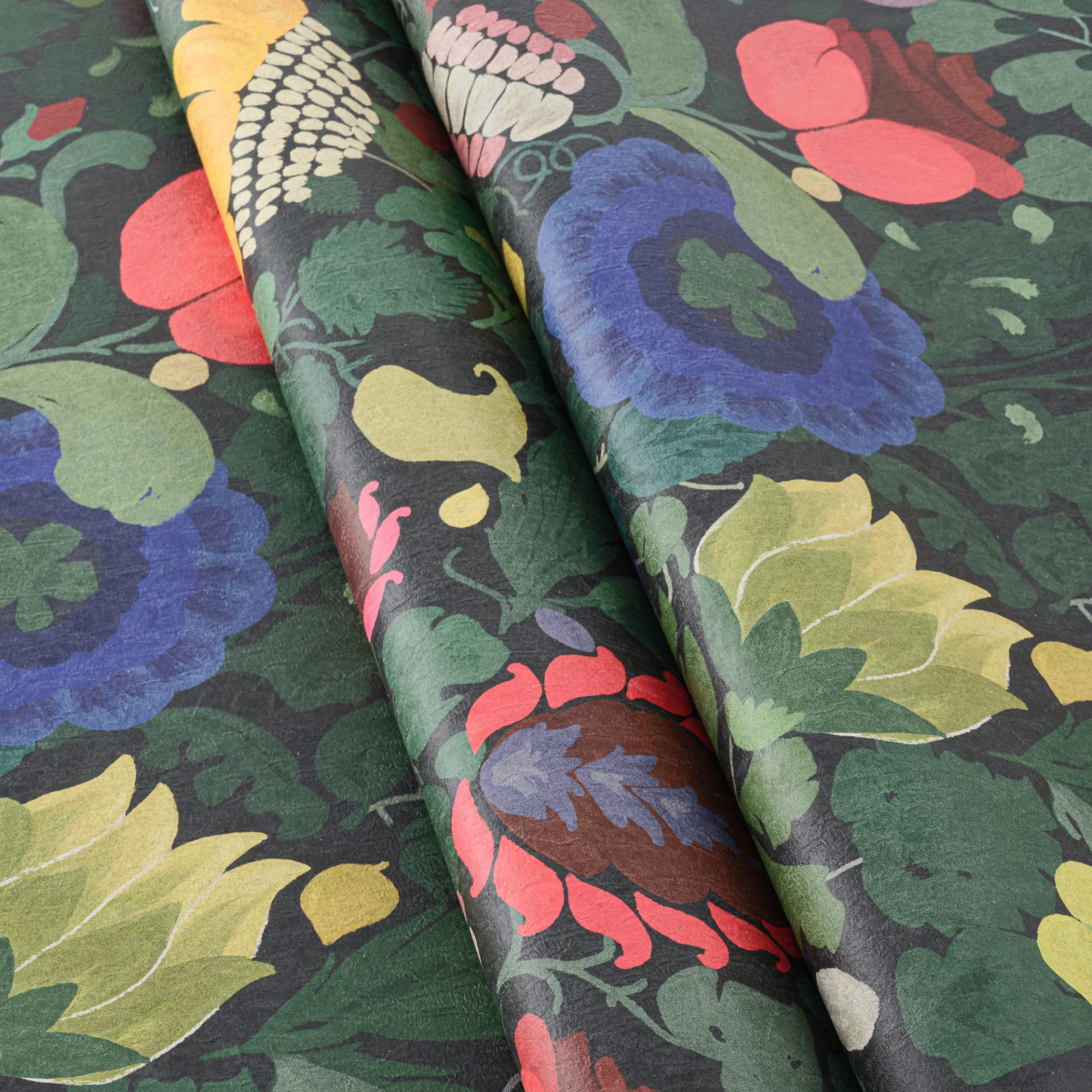 Curved floral wallpaper in dark green, blue, pink and yellow showing the printed pattern and surface detail