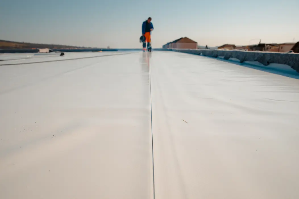 Worker walking on TPO flat roof system installation, South Florida