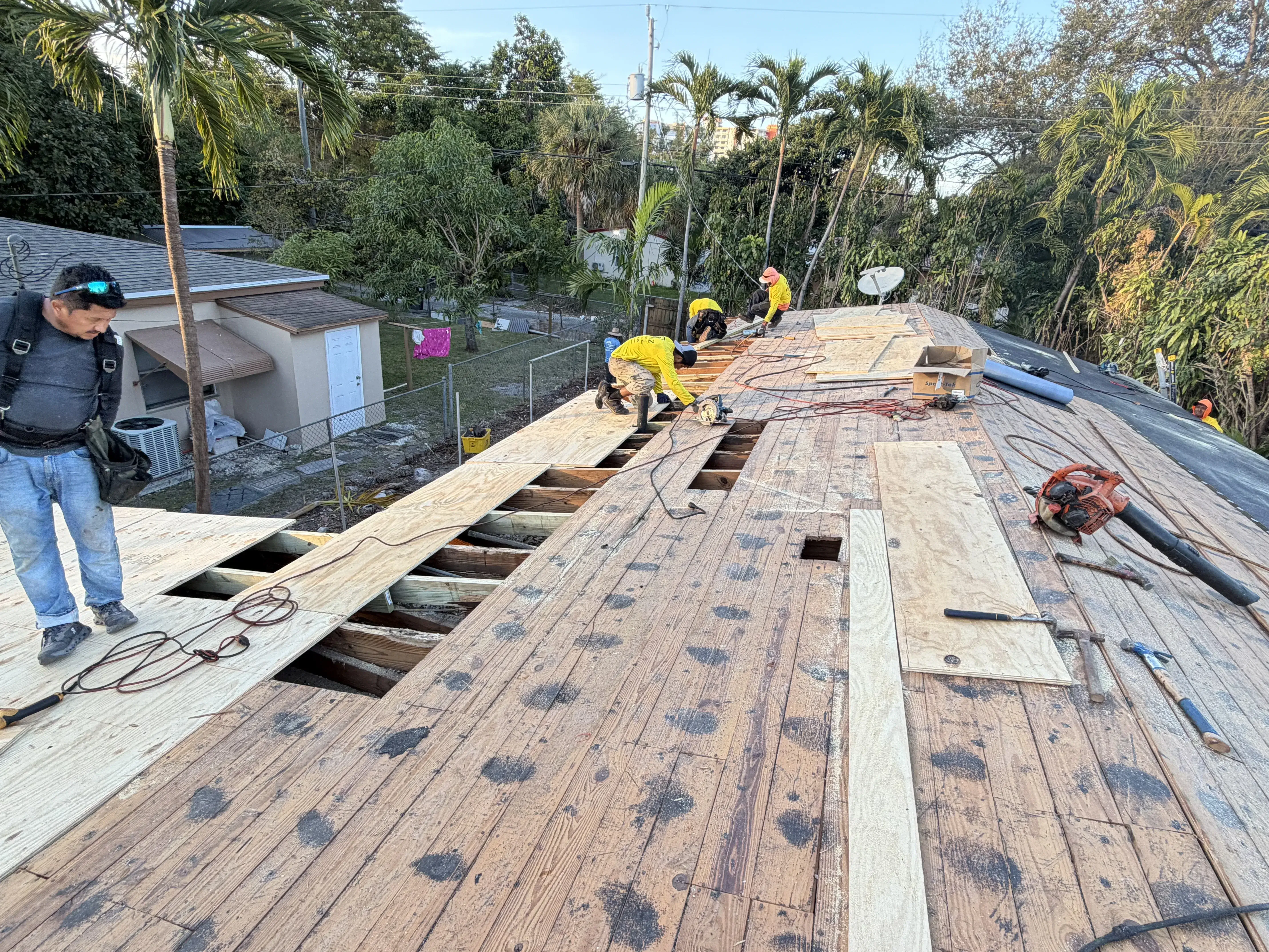 Roofing crew repairing exposed roof decking during roof repair in South Florida