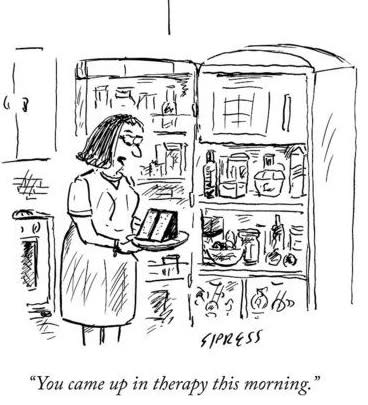 A woman in a kitchen looks at a refrigerator while humorously saying, “You came up in therapy this morning.”