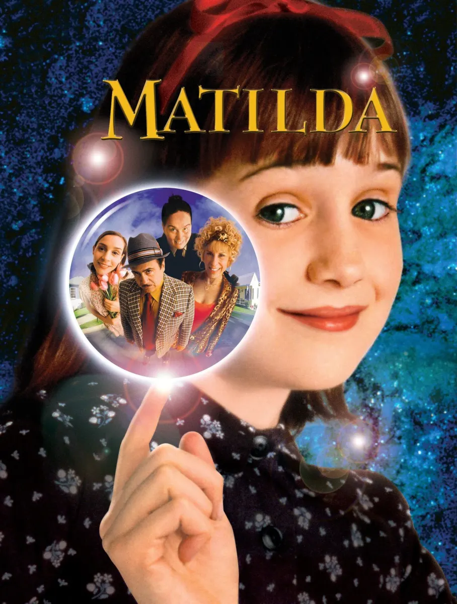 Young girl with brown hair and a red bow, pointing as she magically interacts with characters from Matilda.