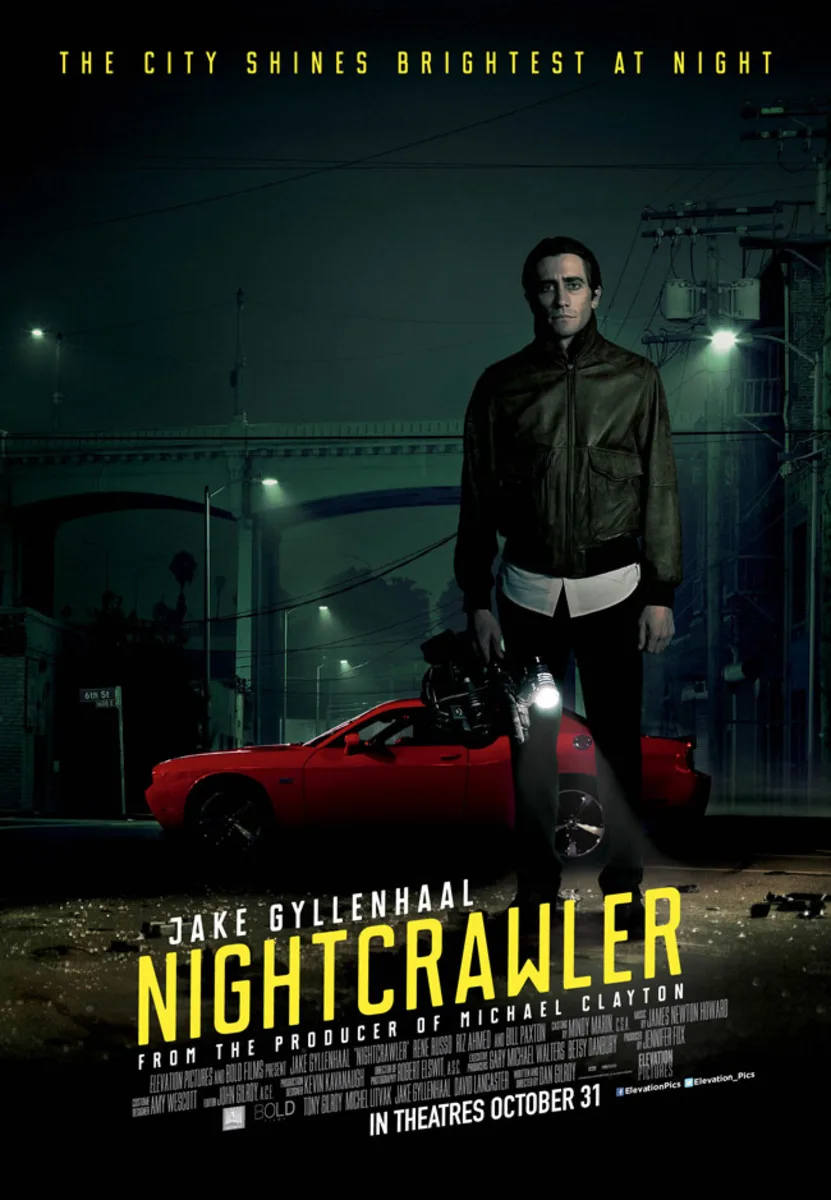 Jake Gyllenhaal stands in a dimly lit urban setting beside a red car, promoting the film Nightcrawler, exploring antisocial behavior.