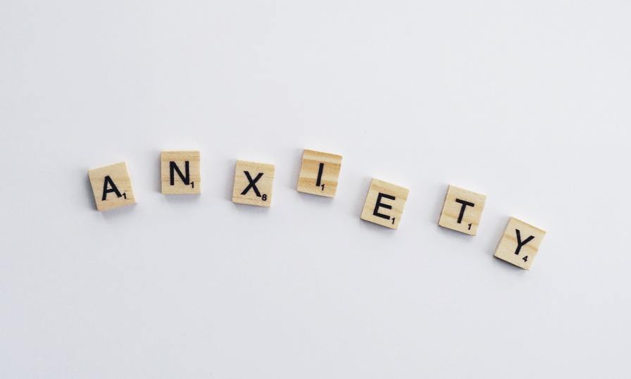 Wooden letter tiles spelling ANXIETY, highlighting a key topic in mental health discussions about managing anxiety.