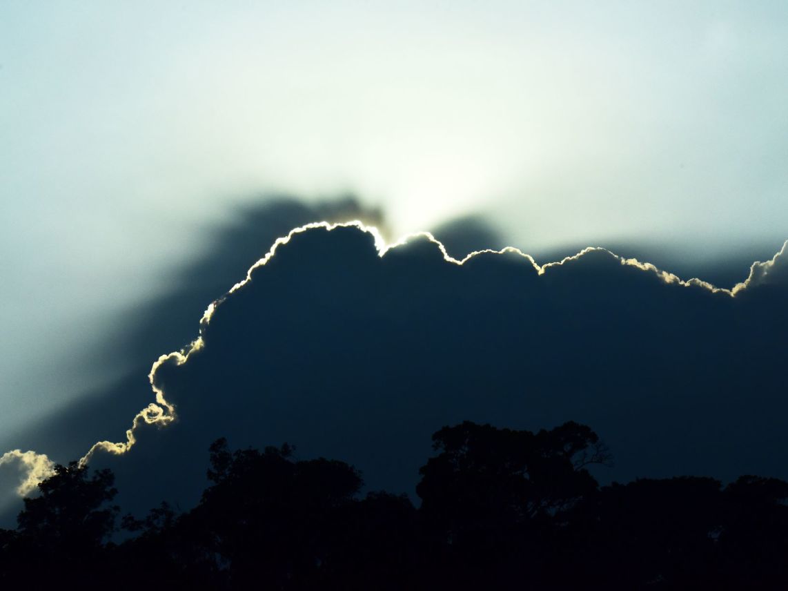 Sunlight peeking through dark clouds at sunset, illustrating the beauty of nature's daily transformations.
