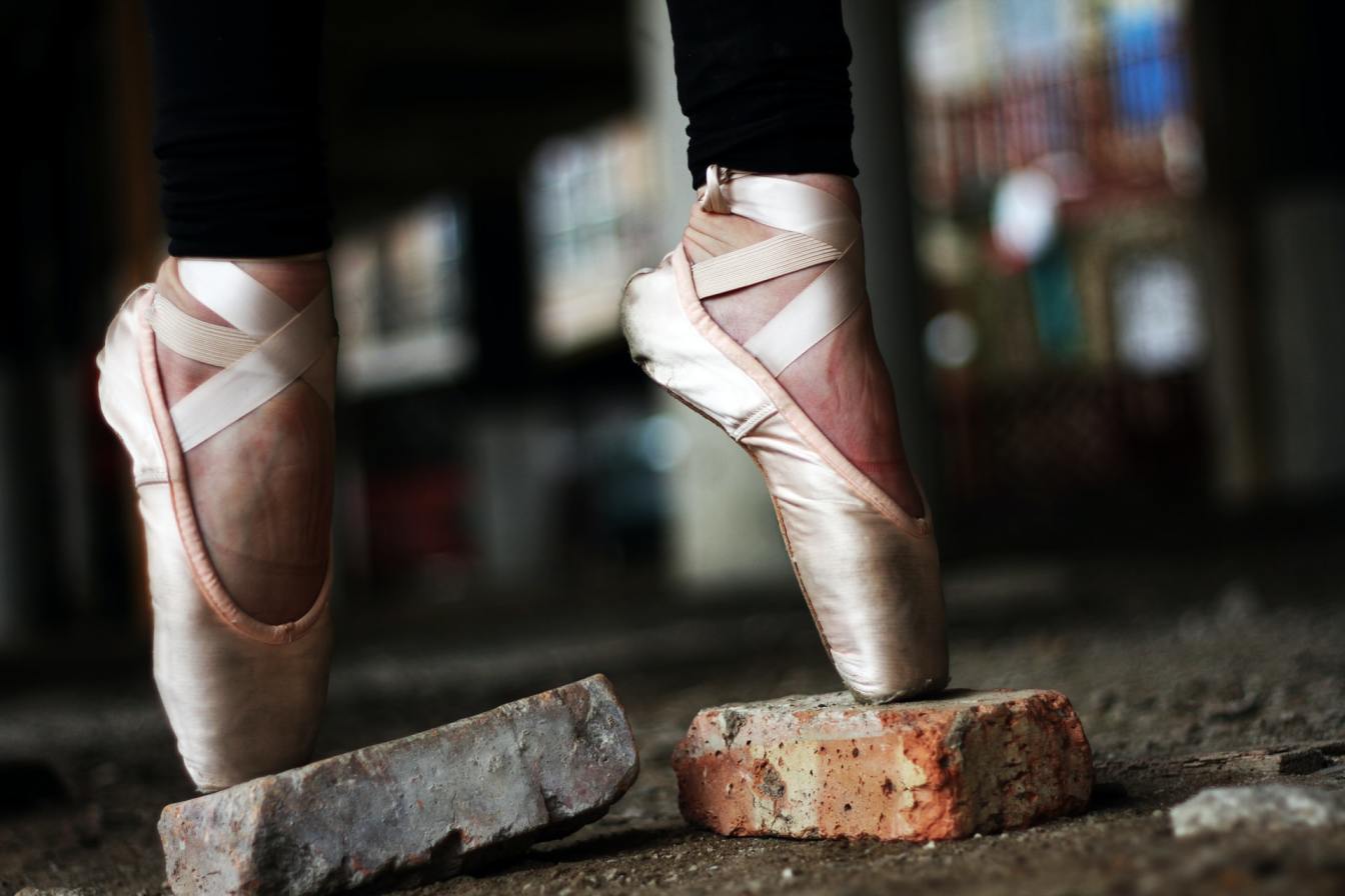 Ballet dancer en pointe on bricks, illustrating the challenges faced in performance and overcoming obstacles in sports.