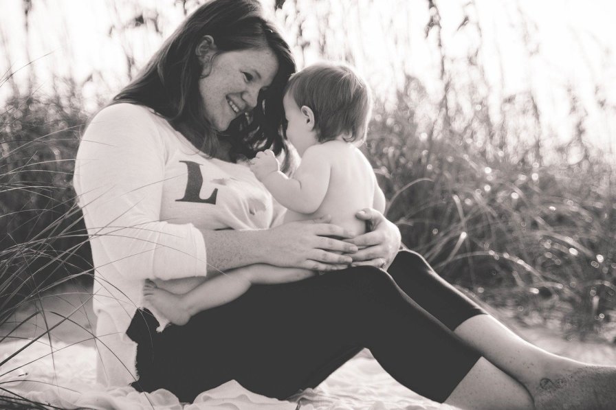 Mother and child playfully interacting on a beach, highlighting attachment and nurturing moments in family life.