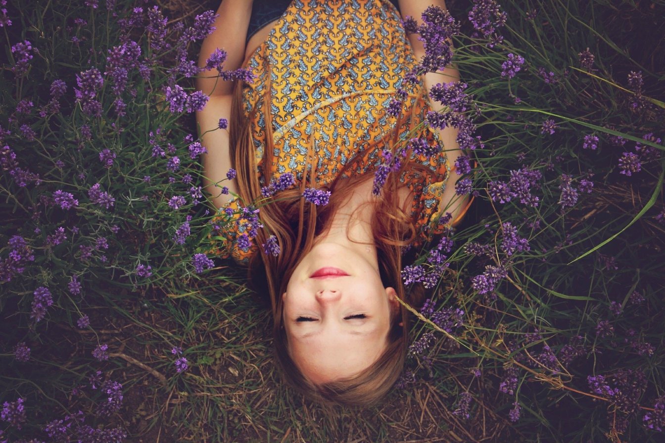 Young woman resting among lavender flowers, eyes closed, embracing mindfulness and tranquility in nature.