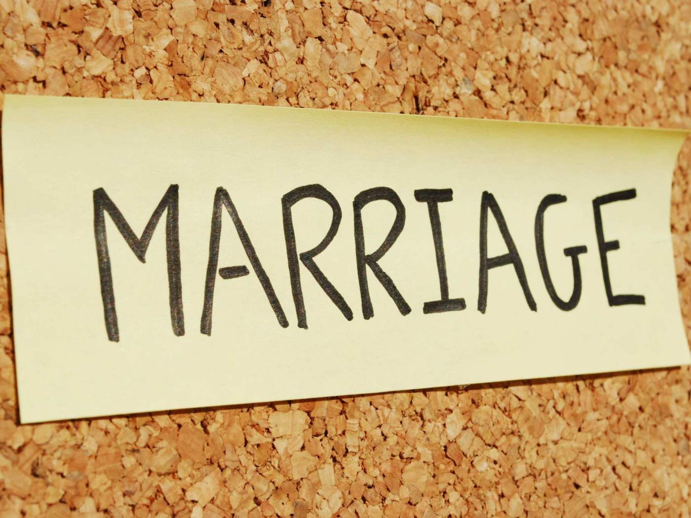 Handwritten note on a corkboard displaying the word MARRIAGE, emphasizing the importance of understanding and improving marital relationships.