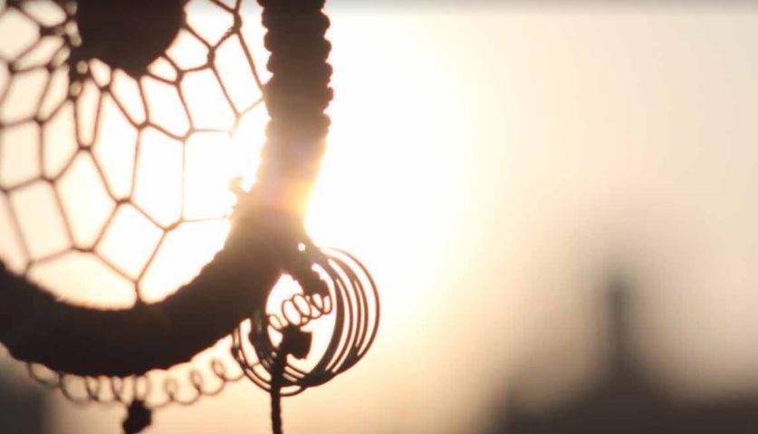 Silhouette of a dreamcatcher against a glowing sunset, symbolizing the intertwining of dreams and personal reflection.
