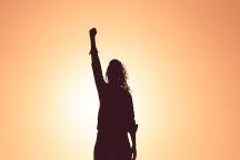 Silhouette of a person raising a fist against a sunset, symbolizing empowerment amidst anxiety and social isolation.