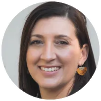 Professional headshot of a psychotherapist with a warm smile, wearing orange earrings.