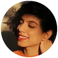 Smiling therapist with curly hair in a warm-toned setting, reflecting a compassionate approach to counseling.