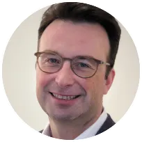 Smiling licensed mental health counselor with glasses, specializing in trauma and life coaching, based in Europe.