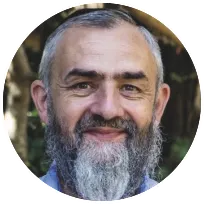 Licensed therapist with a beard, smiling warmly in an outdoor setting, emphasizing supportive therapy for multicultural relationships.