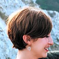 Short-haired young woman smiling outdoors, emphasizing the importance of emotional support for children dealing with behavioral issues.
