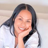 Smiling woman resting her chin on her hand, reflecting on the importance of addressing difficult conversations about discrimination.