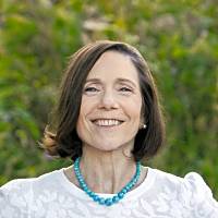 I'm committed to working with individuals and couples in crisis and those seeking personal growth and lasting positive changes in life. Smiling woman with short dark hair wearing a white blouse and turquoise necklace, set against a natural green background.