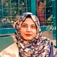 A woman wearing a patterned hijab smiles warmly in a garden setting, reflecting self-acceptance and personal confidence.