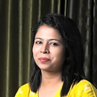 Smiling woman in a yellow top, reflecting a positive mindset and resilience towards life's challenges.