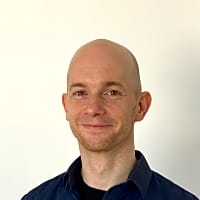 Smiling man with a bald head, wearing a blue shirt, embodying a positive outlook on personal relationships.