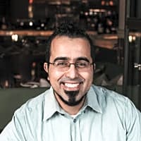 Smiling man in a casual shirt, representing the importance of discussing men's mental health challenges and seeking help.