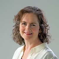 Smiling woman with curly hair, wearing a white shirt, promoting effective communication in relationships.
