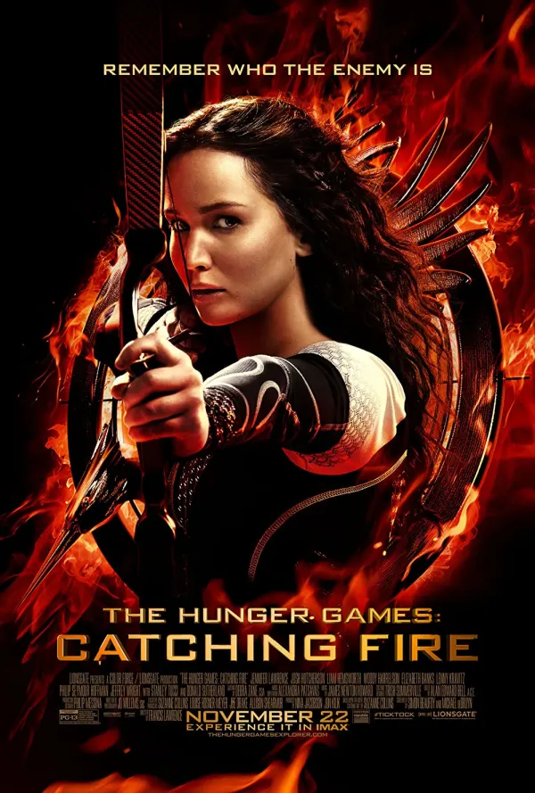 Katniss Everdeen aims her bow against a fiery backdrop in the poster for The Hunger Games: Catching Fire, highlighting themes of conflict.