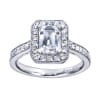 An emerald cut center diamond gleams magnificently encircled in round brilliant diamonds set in a vintage halo engagement ring designed by Gabriel & Co. - Image 1 of 0