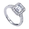 An emerald cut center diamond gleams magnificently encircled in round brilliant diamonds set in a vintage halo engagement ring designed by Gabriel & Co. - Image 4 of 0