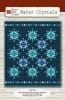 Water Crystals Quilt Pattern by Nancy Rink Designs shows a blue and teal batik quilt with radiating blocks set against a dark, dramatic blue ground and detailed by a narrow top and bottom border. - Image 1 of 0