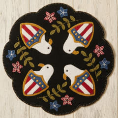EAGLES OF GLORY WOOL MAT PATTERN from Buttermilk Basin shows a black mat with eagle heads and patriot shields with stars sprinkled in.