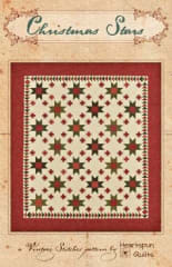 Christmas Stars Quilt Pattern by Heartspun Quilts shows a traditional  star quilt in with small star blocks that surround larger stars, and a flying geeese inner border made in holiday colors.