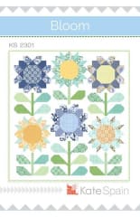Bloom Quilt Pattern by Kate Spain shows 6 large, tall sunflowers in shades of blue , yellow and green on a white background.