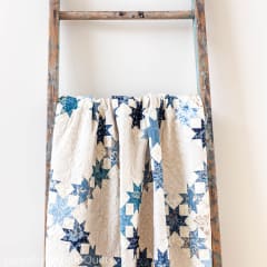 AURORA Quilt Pattern by Laundry Basket Quilts  shows a traditional 
 star quilt in shades of blue,and cream.