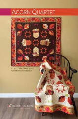Acorn Quartet by Robin Pickens shows a fall wall hanging featuring 4 Acorns and shows the quilt made with a dark background as well as one made with a light background.