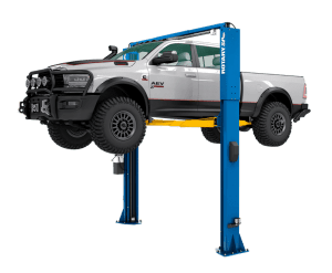 Rotary SPO12-AV 12,000 lb. capacity two-post lift raising a silver RAM 2500 heavy-duty pickup truck. The image showcases the blue Double S columns and yellow All-Vehicle (AV) arms, designed for high-ground-clearance trucks and EVs.