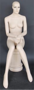 Flesh-tone fiberglass sitting female mannequin with realistic hand-painted blue eyes, pierced ears, and rotating arms, showcasing apparel in a retail display.