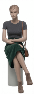 Realistic seated female fiberglass mannequin with light flesh tone skin, hand-painted facial features, and molded hair for stylish retail apparel display.