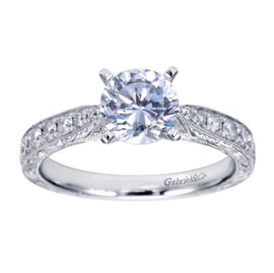 A round center diamond sits perfectly in a vintage inspired straight engagement ring with side round brilliant diamonds.
