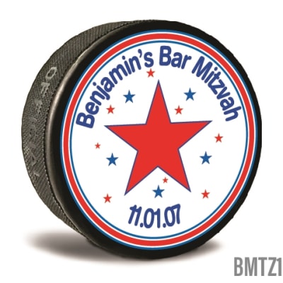 A custom printed hockey puck is personalized in bright colors and text written to personalize it for the recipients. Celebrate your Bar Mitzvah and  let guests take home a memory.