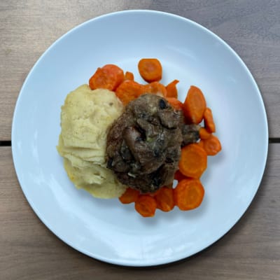 Savor a hearty gluten-free Salisbury steak dinner with a flavorful beef patty, mushroom gravy, mashed potatoes, and carrots, perfect for comfort food cravings without the gluten.
