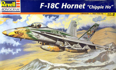 Box art illustration of scale model F-18C Hornet 'Chippie Ho', the CAG plane of the VF 195 streaking through the stormy sky with mountains below.