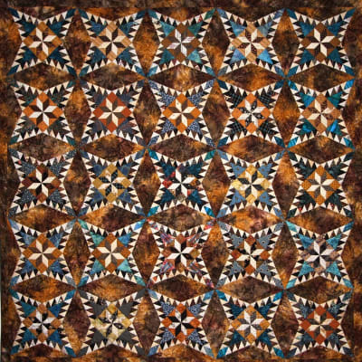 Maryam Quilt Pattern by Laundry Basket Quilts  shows a pine burr quilt in shades of blue and brown.