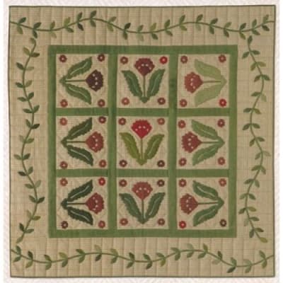 This quilt image shoes a primitive style appplique quilt featuring a flower with a straight sash setting and a meandering vine border.